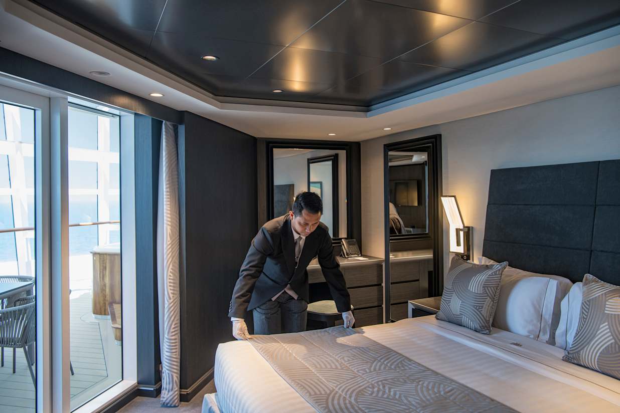 Butler making the bed in a Yacht Club Cabin on MSC World Europa